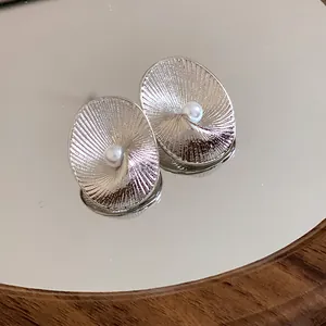 Detailed view of silver-tone oval earrings with radial texture and central pearl