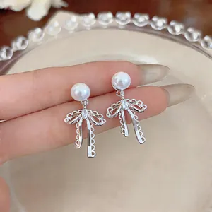 Close-up of elegant French style bow-knot earrings with white pearls and lace details