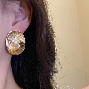Detailed view of elegant oval textured 18k gold plated stud earring with central pearl