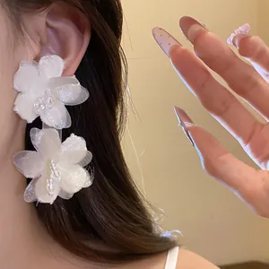 Detail shot of elegant white fabric flower earrings with delicate beaded stamen accents