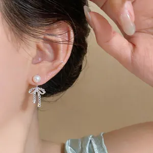 Detailed view of French style silver bow earrings with elegant pearl worn on ear lobe