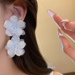 Close-up detail of elegant white floral tulle earrings with pearl accents on a model
