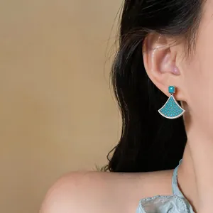 Detailed view of elegant blue fan-shaped earrings worn by a model for a chic luxury look