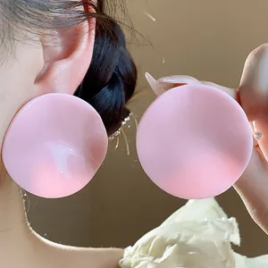 Detailed shot of oversized pink acrylic round earrings with wavy surface design