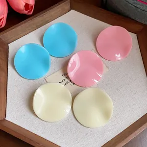Close-up of acrylic wrinkled round earrings in blue, pink and cream colors on tray