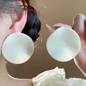 Detailed macro shot of elegant large white wavy acrylic stud earrings worn on model ear