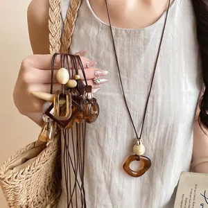 Bohemian retro amber resin oval pendant necklace with long dark brown leather cord.