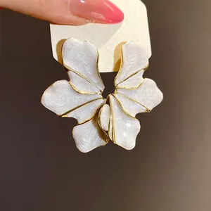 Detailed close-up of a white flower petal earring with golden edges and glitter finish.