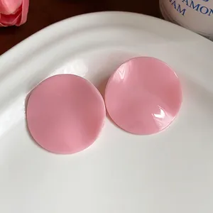 Macro view of pink acrylic round stud earrings with unique crumpled surface texture