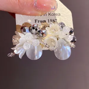 Eleganti orecchini a lobo con fiori di cristallo e perle a goccia con dettagli lucidi.
