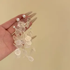Détail de boucles d'oreilles pendantes en nacre et perles blanches au design élégant