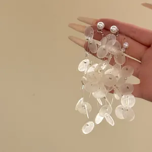 Gros plan de boucles d'oreilles vintage françaises en coquillage blanc et perle à la main.