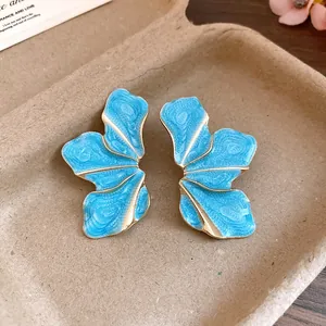 Macro view of stylish blue flower stud earrings with golden alloy wavy metal edges