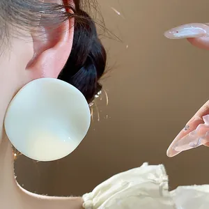Close-up of a white acrylic round stud earring with a textured wrinkled surface