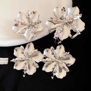Detailed view of polished silver flower rings and earrings with vintage metallic finish