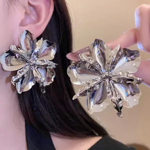 Detailed macro view of oversized metallic flower earrings with a polished silver finish