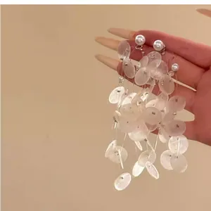 Gros plan de disques de nacre blanche et de perles sur d'élégantes boucles d'oreilles.