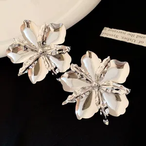 Close-up of metallic glossy flower stud earrings with vintage silver finish