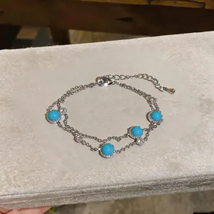 Detail eines silbernen Doppelarmbands im Vintage-Stil mit runden Türkis- und Zirkonsteinen.