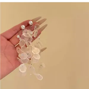 Détail de boucles d'oreilles à pompons vintage avec des coquillages blancs et perles