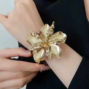 Detailed view of a high-end glossy gold flower cuff bracelet worn on a female wrist