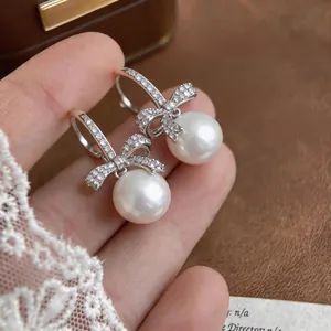 Dettaglio di eleganti orecchini a fiocco in argento con zirconi e perle bianche