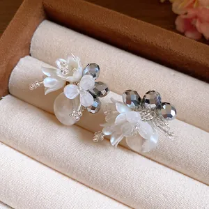 Primo piano di eleganti orecchini a lobo a fiore di cristallo con perle a goccia