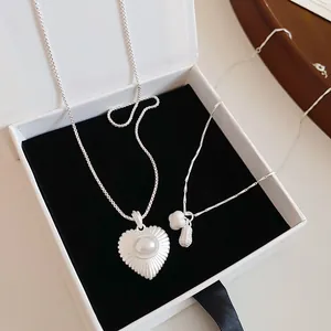 Elegant silver-toned necklace set featuring heart pearl and peanut charms in a box