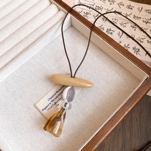 Close-up detail of handcrafted resin pendant necklace with brown leather cord strap.