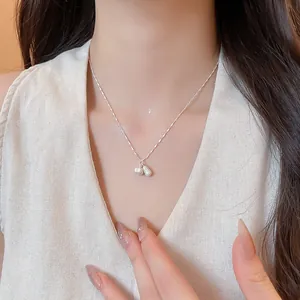 Close-up of elegant silver necklace with peanut and pearl pendants on model's neck