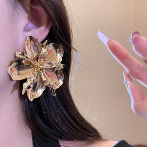 Close-up view of a large gold metallic flower earring worn on a model ear, vintage style.