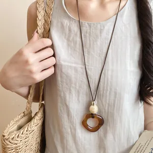 Close-up of resin oval pendant necklace worn with a minimalist summer linen dress.