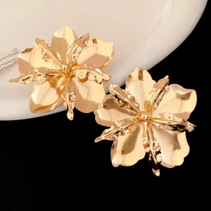 Detailed close-up of vintage metallic gold flower stud earrings with glossy finish