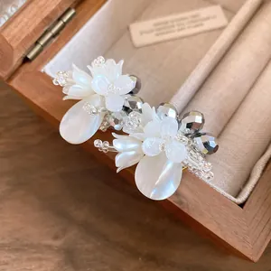 Dettaglio di eleganti orecchini a fiore in cristallo bianco con petali madreperla