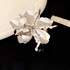 Macro detail of high-shine metallic flower open ring with sculptural petals and silver finish