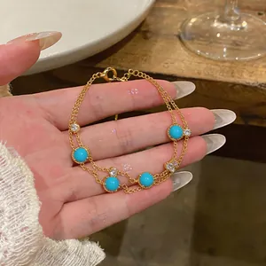 Nahaufnahme eines goldenen zweilagigen Armbands im französischen Retro-Stil mit blauen Perlen
