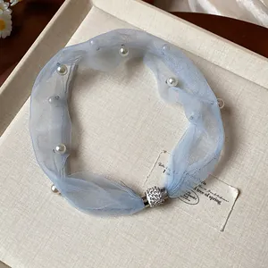 Dettaglio choker in rete blu con perle e chiusura magnetica con strass scintillanti