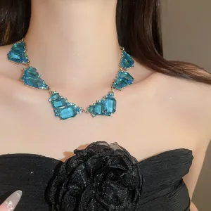 Close-up detail of a vintage court style geometric blue crystal statement necklace on a model