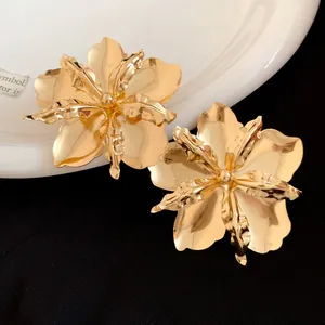 Detailed view of oversized gold metallic flower earrings with vintage textured petals.