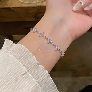 Nahaufnahme eines silberfarbenen Armbands mit rosa Zirkonia-Blüten am Handgelenk.