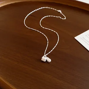 Detailed macro view of silver peanut and heart charms on a delicate silver chain necklace