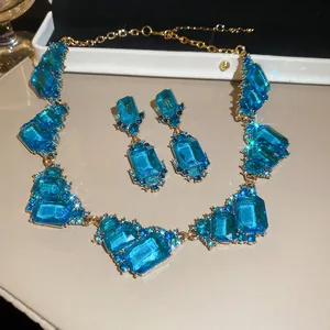Close-up of vintage royal jewelry set featuring emerald-cut blue crystals in gold setting.