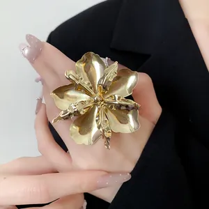 Close-up shot of a large gold metallic flower statement ring worn on a model's hand