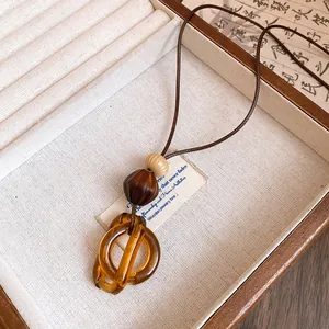 Detailed macro view of a brown resin double ring pendant necklace in a wooden box
