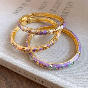 Close-up detail of luxury vintage gold bangles featuring enamel flowers and crystals