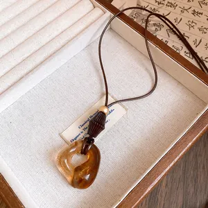 Amber-colored resin donut pendant on a brown cord necklace, minimalist jewelry detail