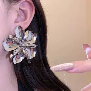 Close-up of an exaggerated metallic silver flower earring showing glossy texture