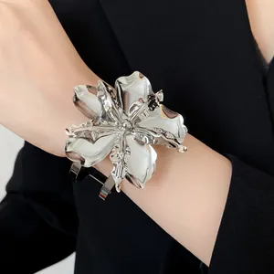 Macro close-up of a large silver metallic flower cuff bracelet on wrist, vintage style