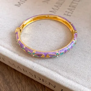 Detailed view of a purple enamel floral bangle with gold-tone metal and rhinestones