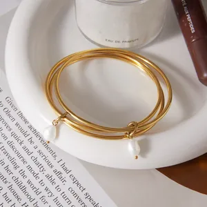 Detailed view of stackable gold-plated stainless steel rings with elegant pearl charms.